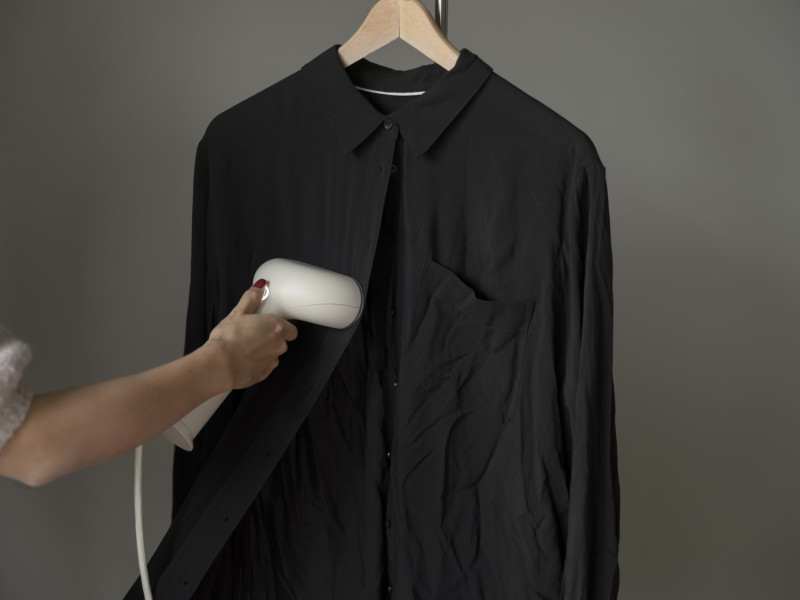 Person using a steamer on a black shirt
